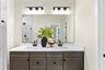 bathroom with two sinks and brown cabinets and black hardware, mirror