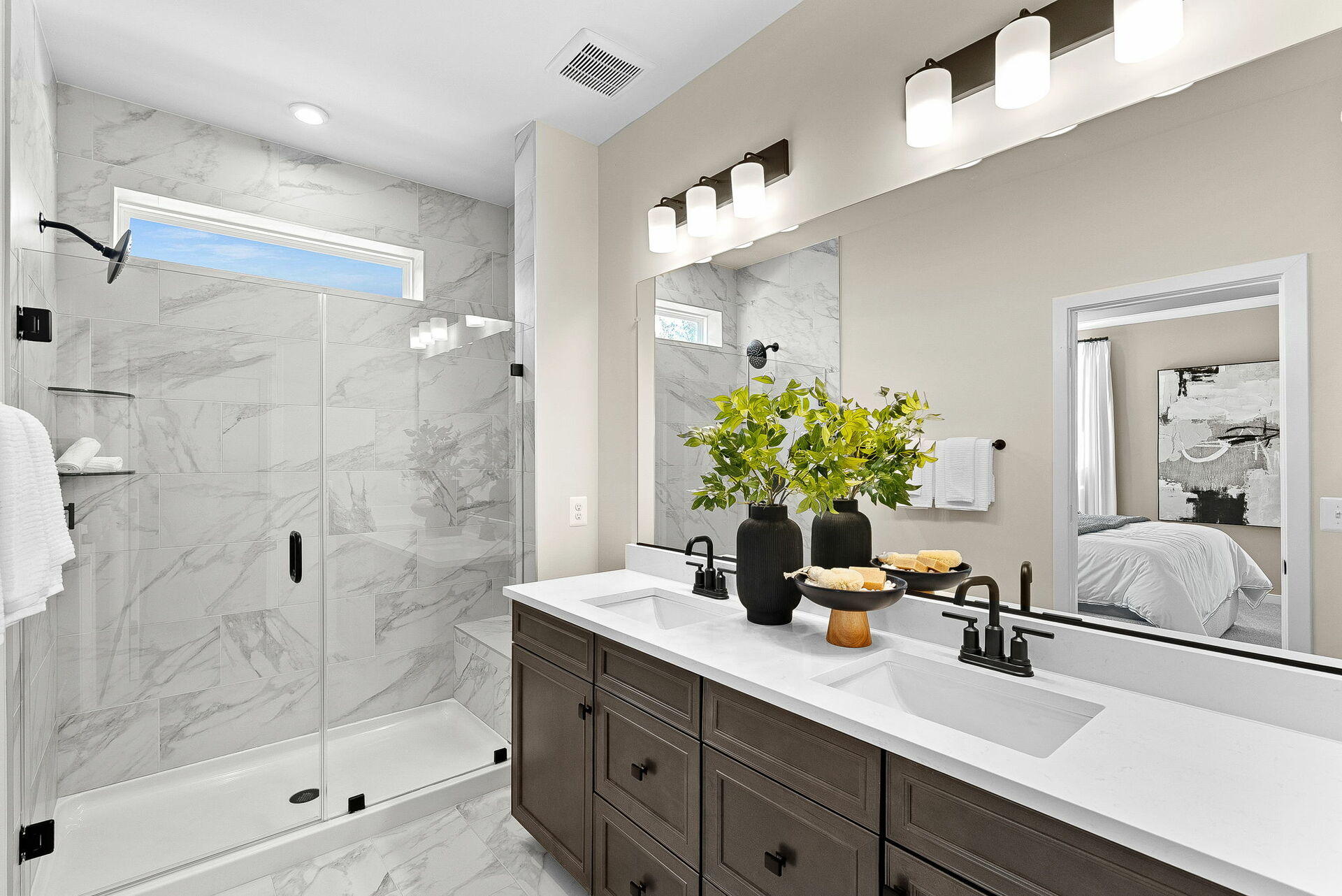 bathroom with two sinks, brown cabinets and black hardware and tile with shower