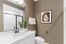 bathroom with sink with black hardware, white quartz, white cabinets, and toilet