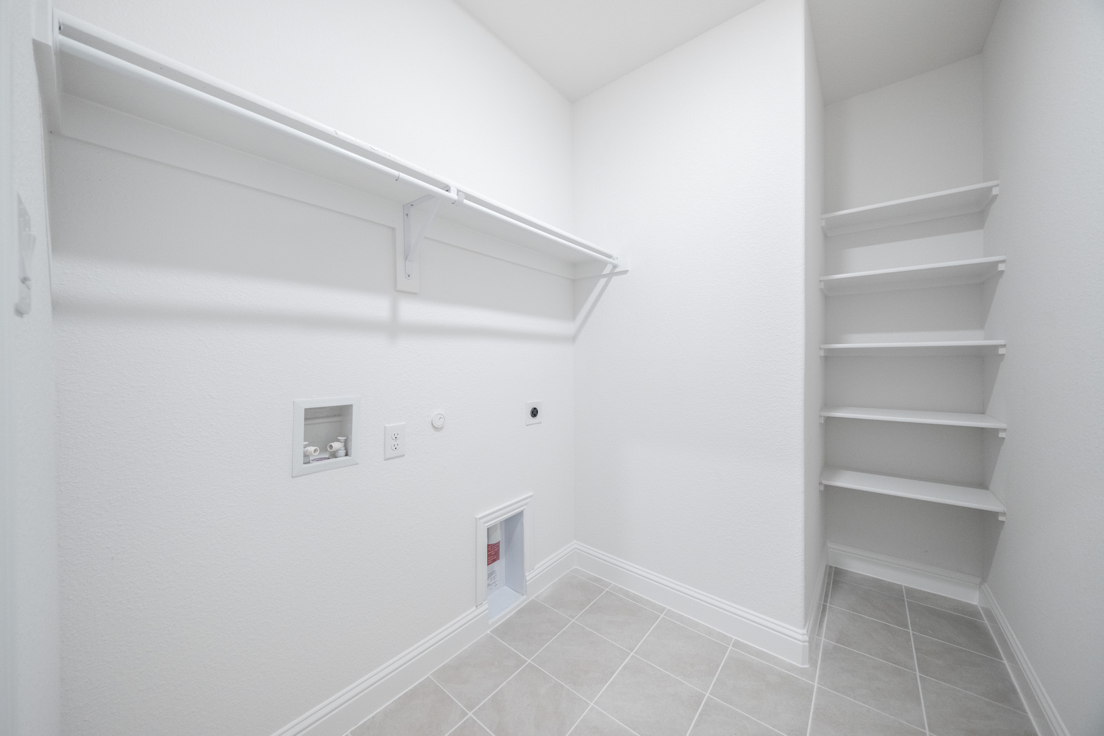 laundry room with tile flooring and storage shelving