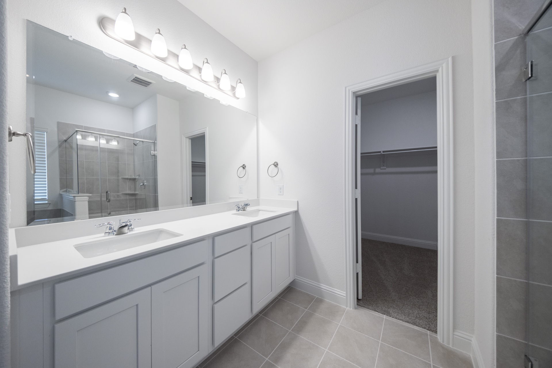 primary bathroom with double sinks with tile flooring