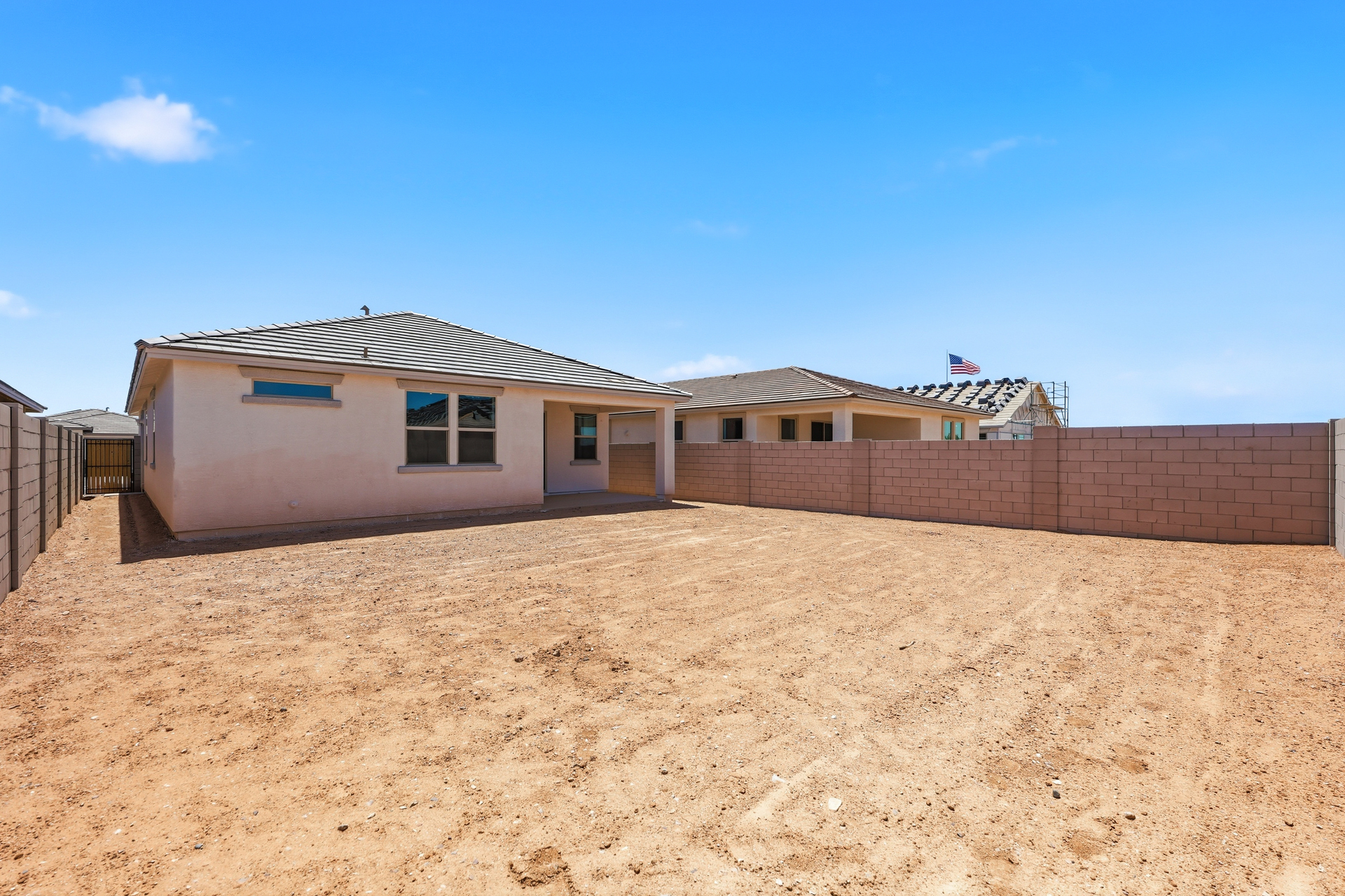 spacious dirt backyard with a concrete block wall