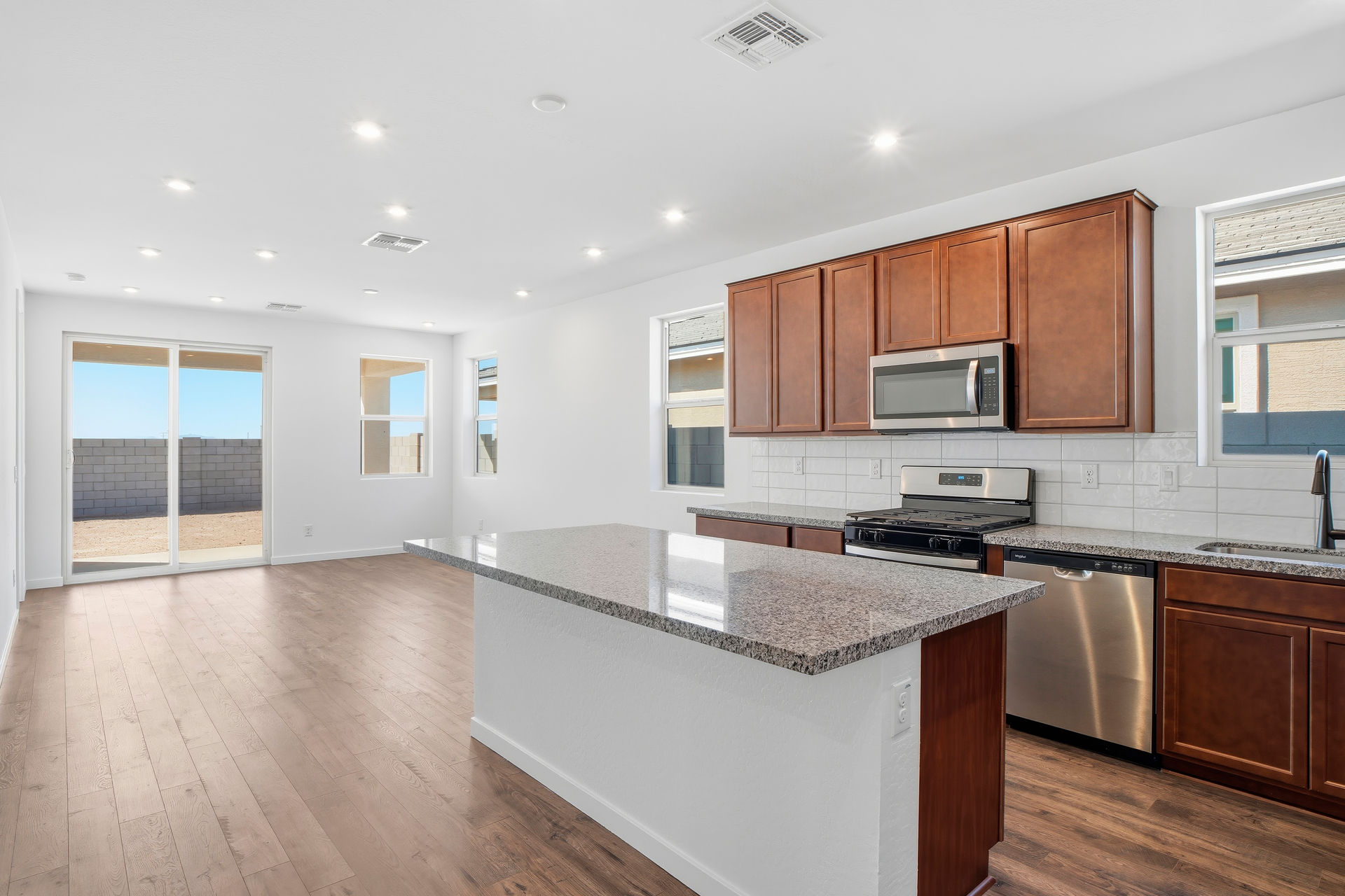 kitchen with brown cabinets, new caledonia countertops, and stainless-steel appliances.