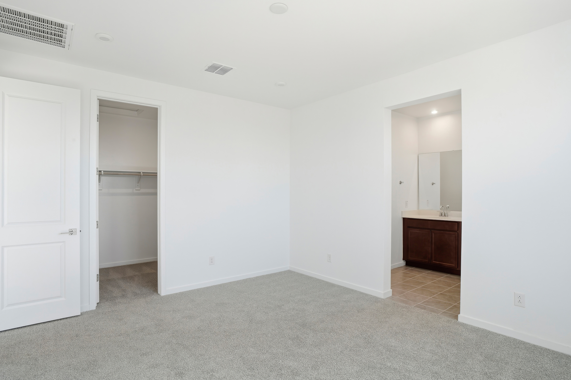 spacious bedroom with light grey carpet and natural light