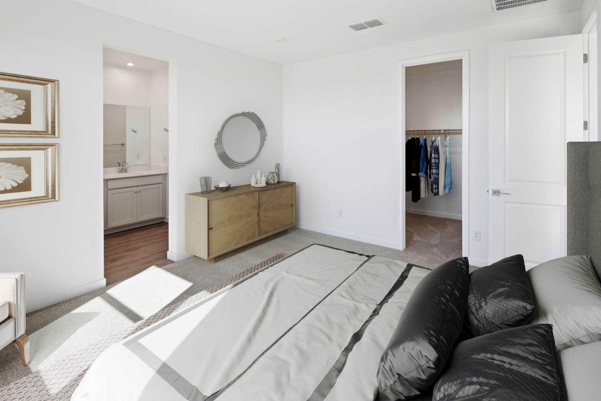 spacious bedroom with a large bed with silk black bed sheets, a wooden dresser, round mirror