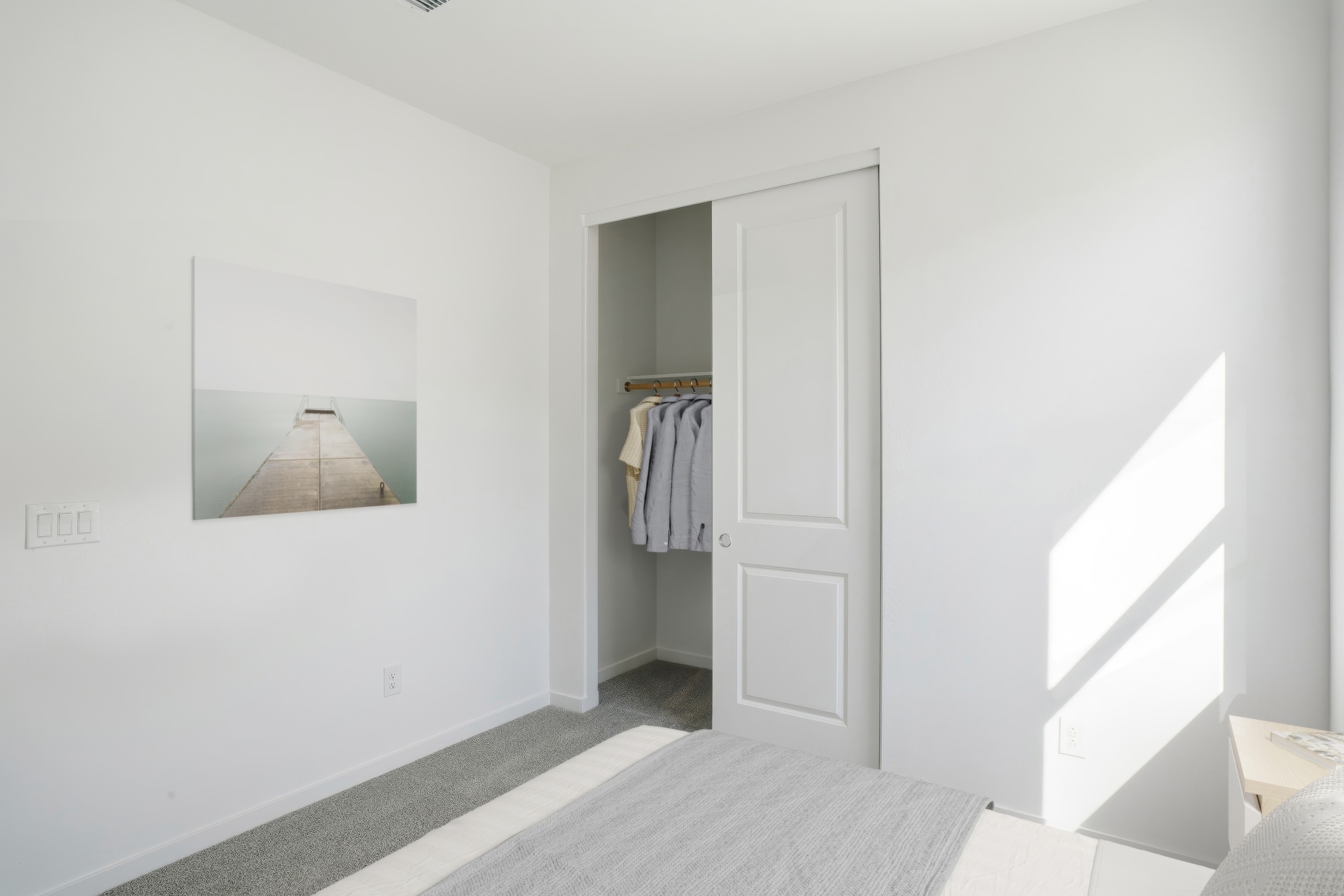 bedroom with a large bed, artwork on the wall, and a closet with a sliding door