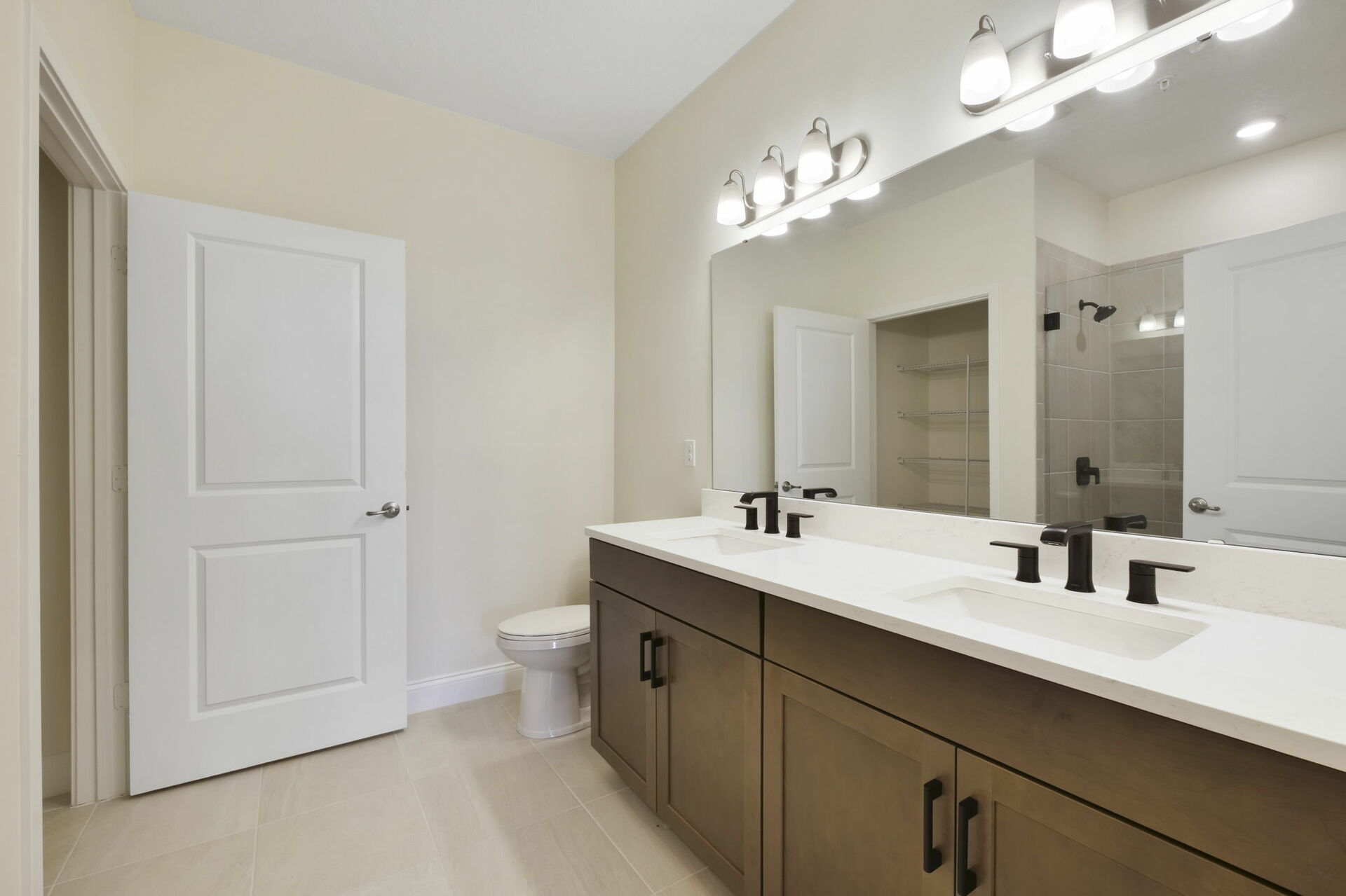 dual sink vanity with large mirror, water closet, shower and linen closet