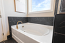primary bathroom with black mosaic tile, wood cabinets, and gold hardware