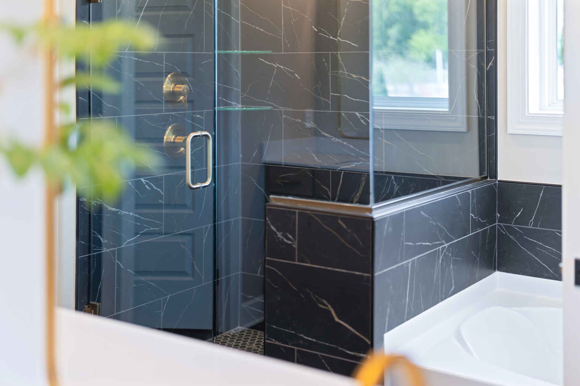primary bathroom with black mosaic tile, wood cabinets, and gold hardware