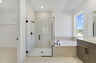 primary bathroom with dual sink vanity, semi-frameless shower, and tub