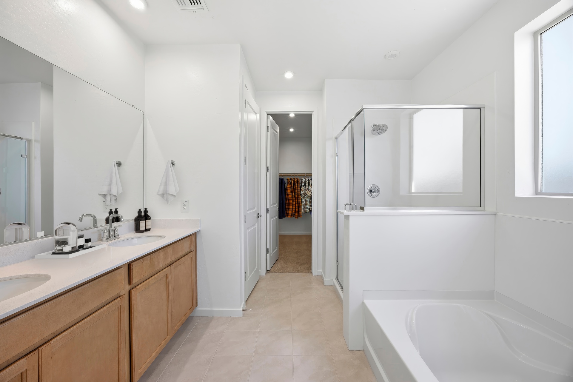 spacious bathroom with light brown cabinets, walk-in shower, and soaking tub