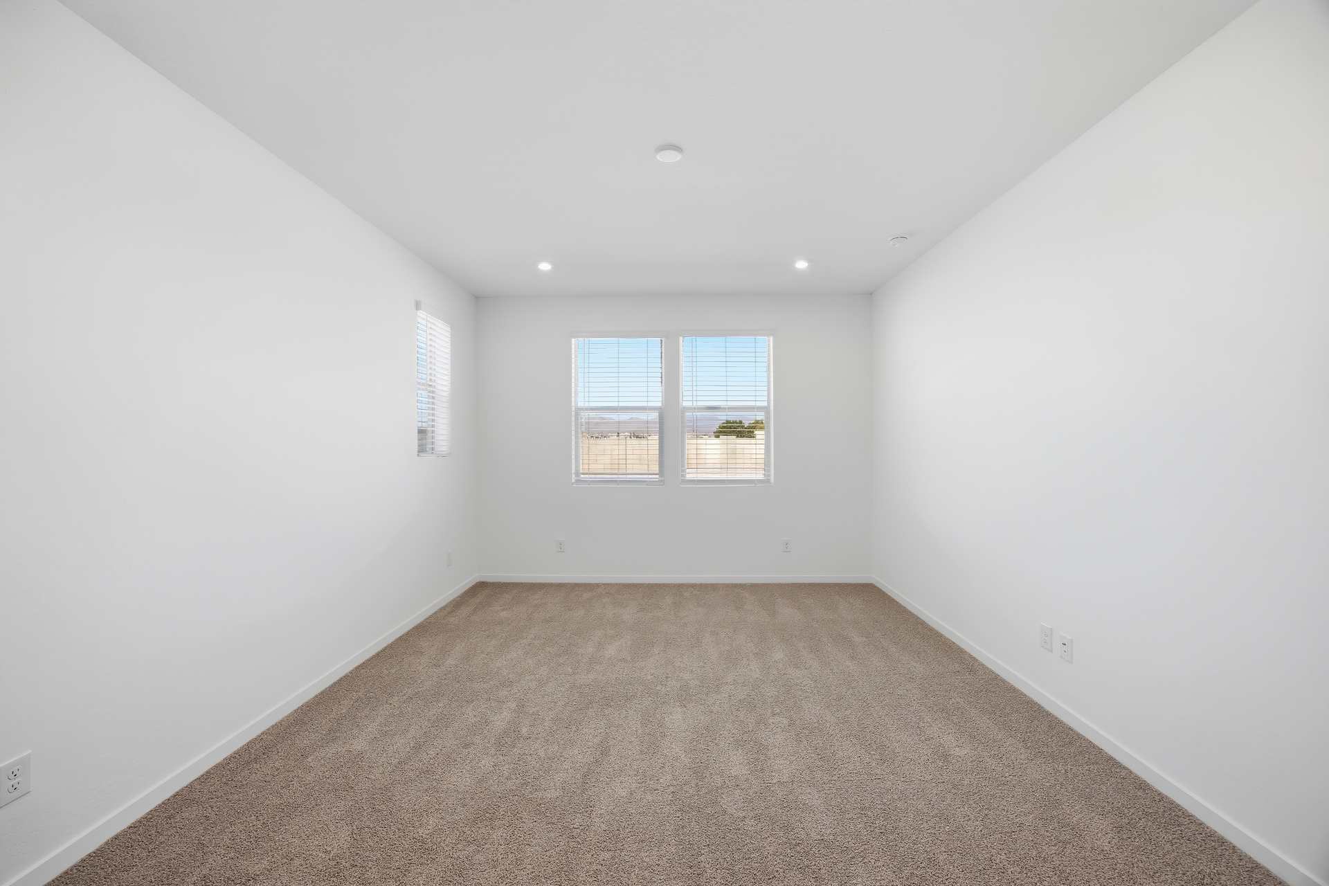 spacious bedroom with light brown carpet and windows for natural light