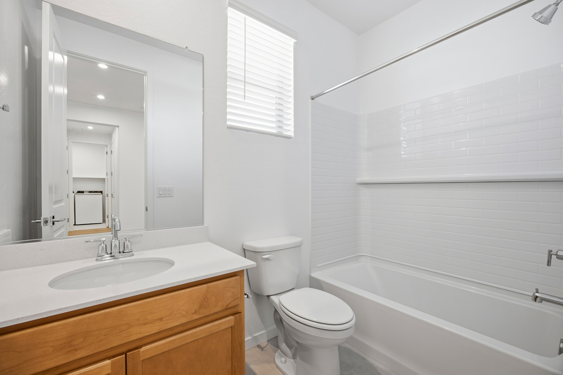 bathroom with light brown cabinets, white countertop, and chrome faucet
