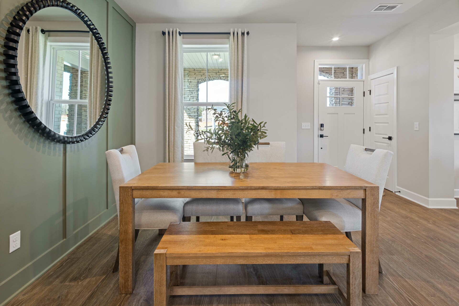dining room with wood flooring, green accent wall, dining room table with chairs, and a window
