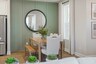 dining room with wood flooring, green accent wall, dining room table with chairs, and a window