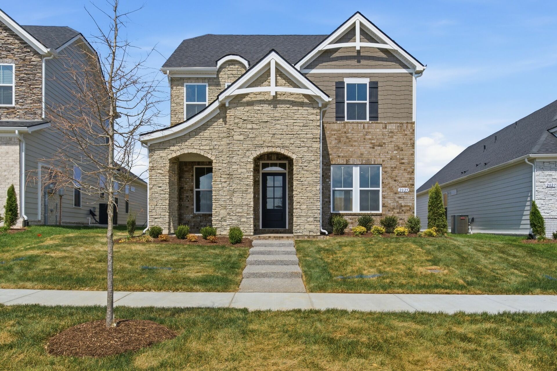 exterior with brick, stone, and covered front porch