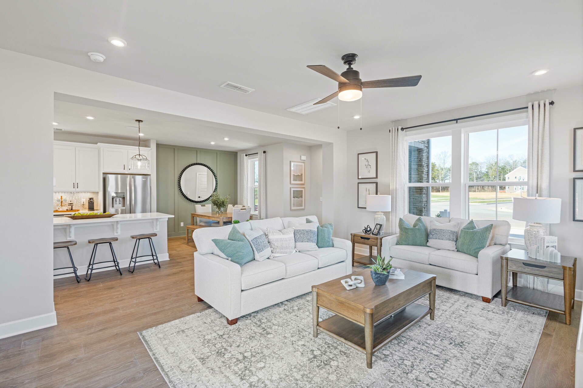 great room with white sofas, wood flooring, accent furniture, and large windows