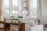 great room with white sofas, wood flooring, accent furniture, and large windows
