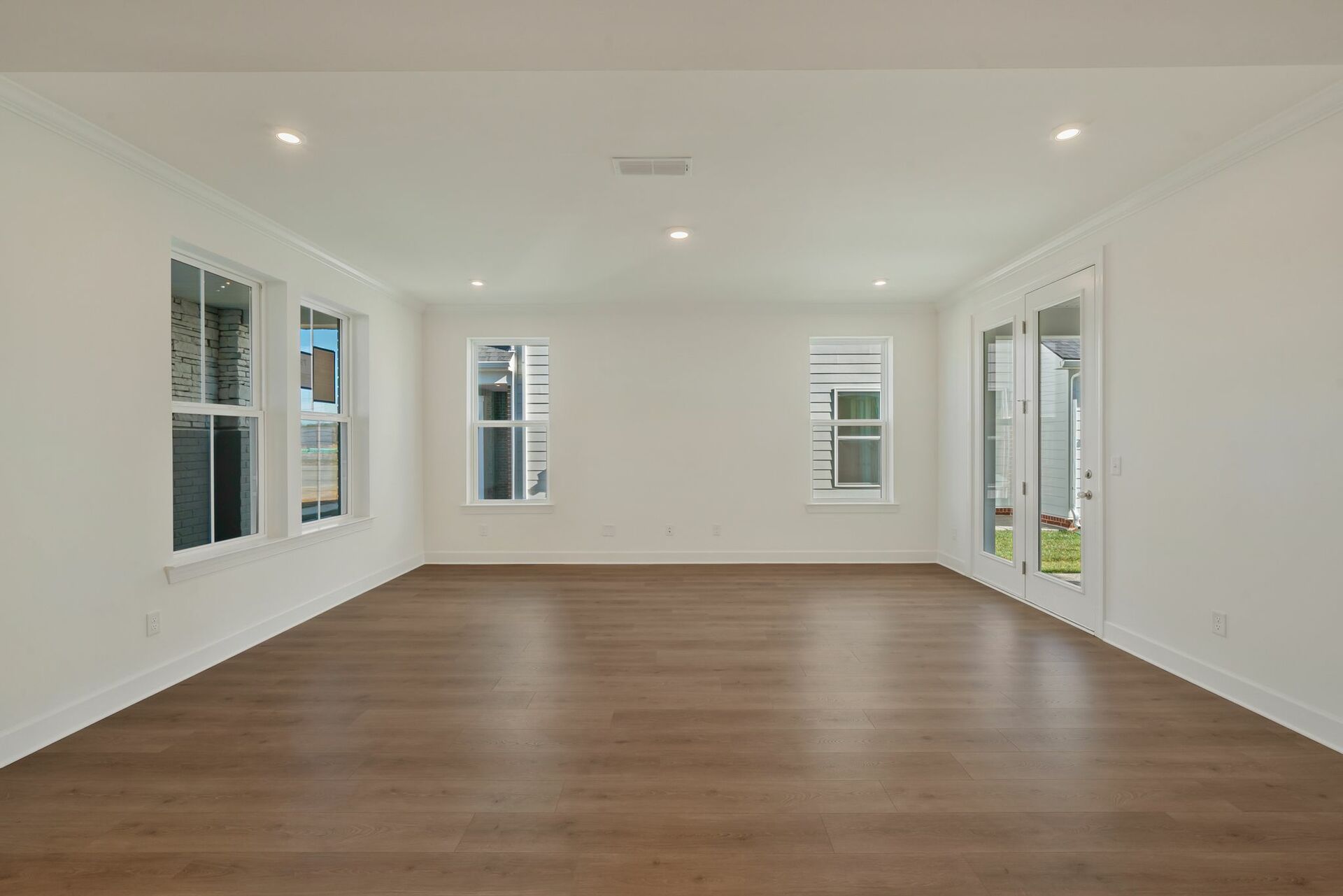 great room with wood floors, white walls and large windows