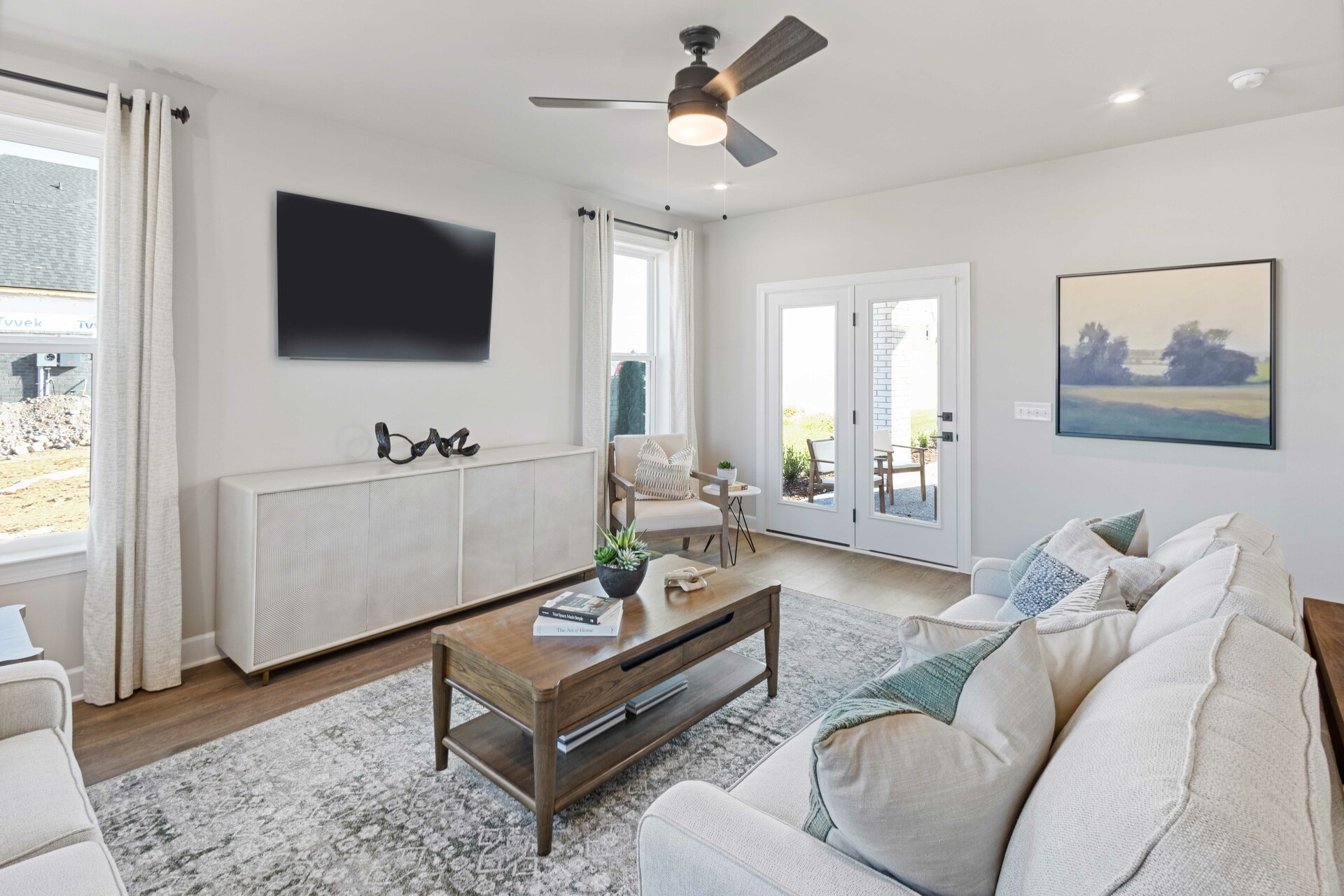 great room with white sofas, wood flooring, accent furniture, and large windows