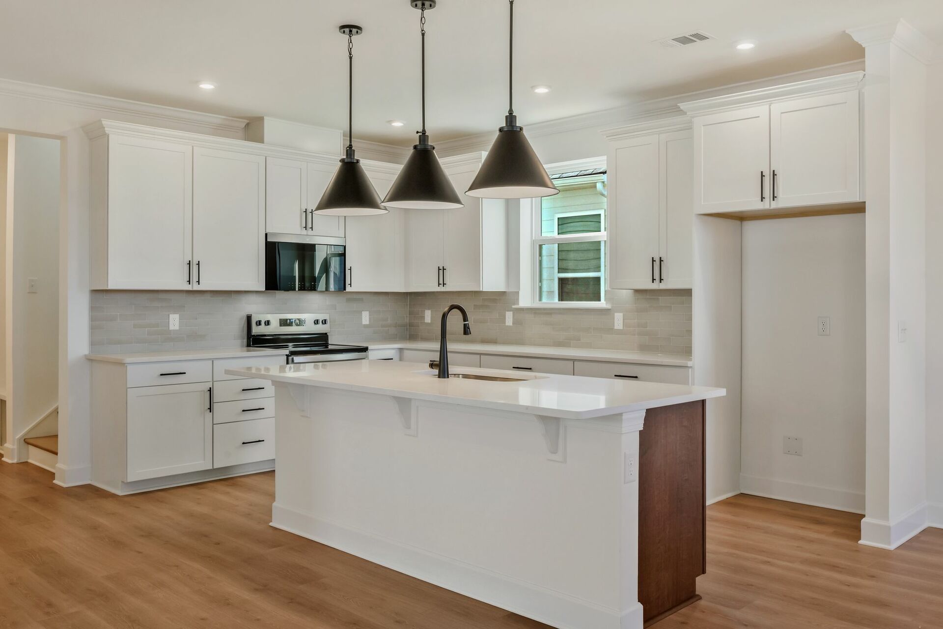 kitchen with white cabinets, island with wood cabinets, and black hardware