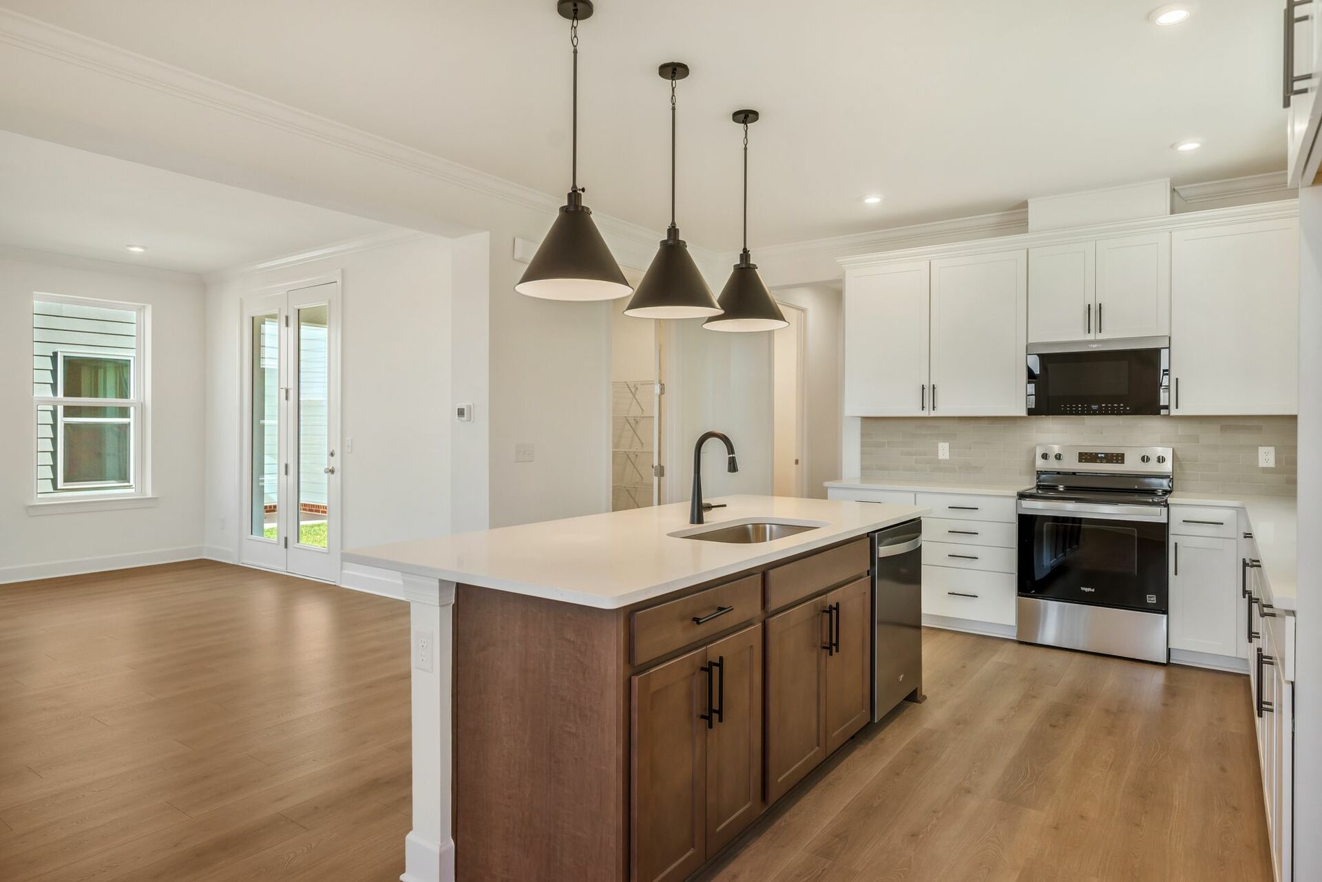 kitchen with white cabinets, island with wood cabinets, and black hardware
