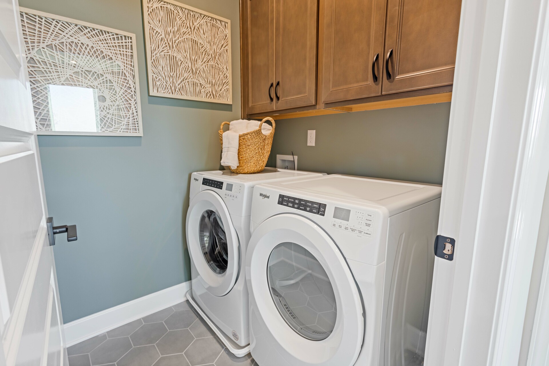 laundry room with tile flooring, wood cabinets, and white washer and dryer