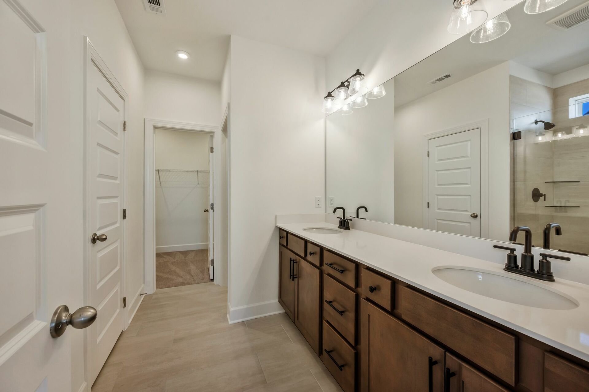bathroom with double sink vanity, wood cabinets and black hardware