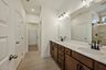 bathroom with double sink vanity, wood cabinets and black hardware