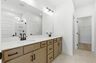 primary bathroom with double sink vanity, wood cabinets, and white countertops