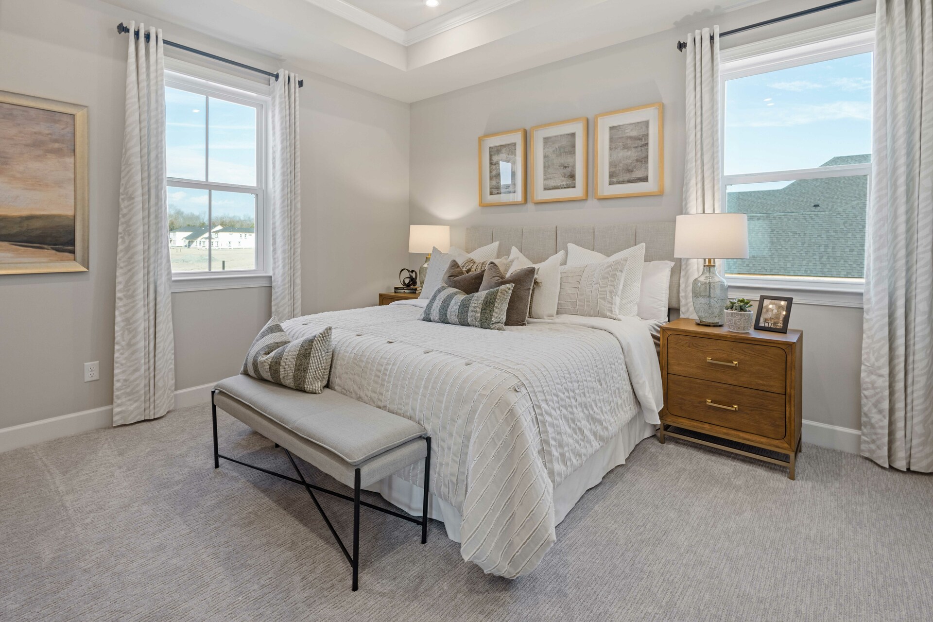 primary bedroom with large bed, nightstands, large windows, and a tray ceiling