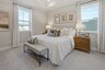 primary bedroom with large bed, nightstands, large windows, and a tray ceiling
