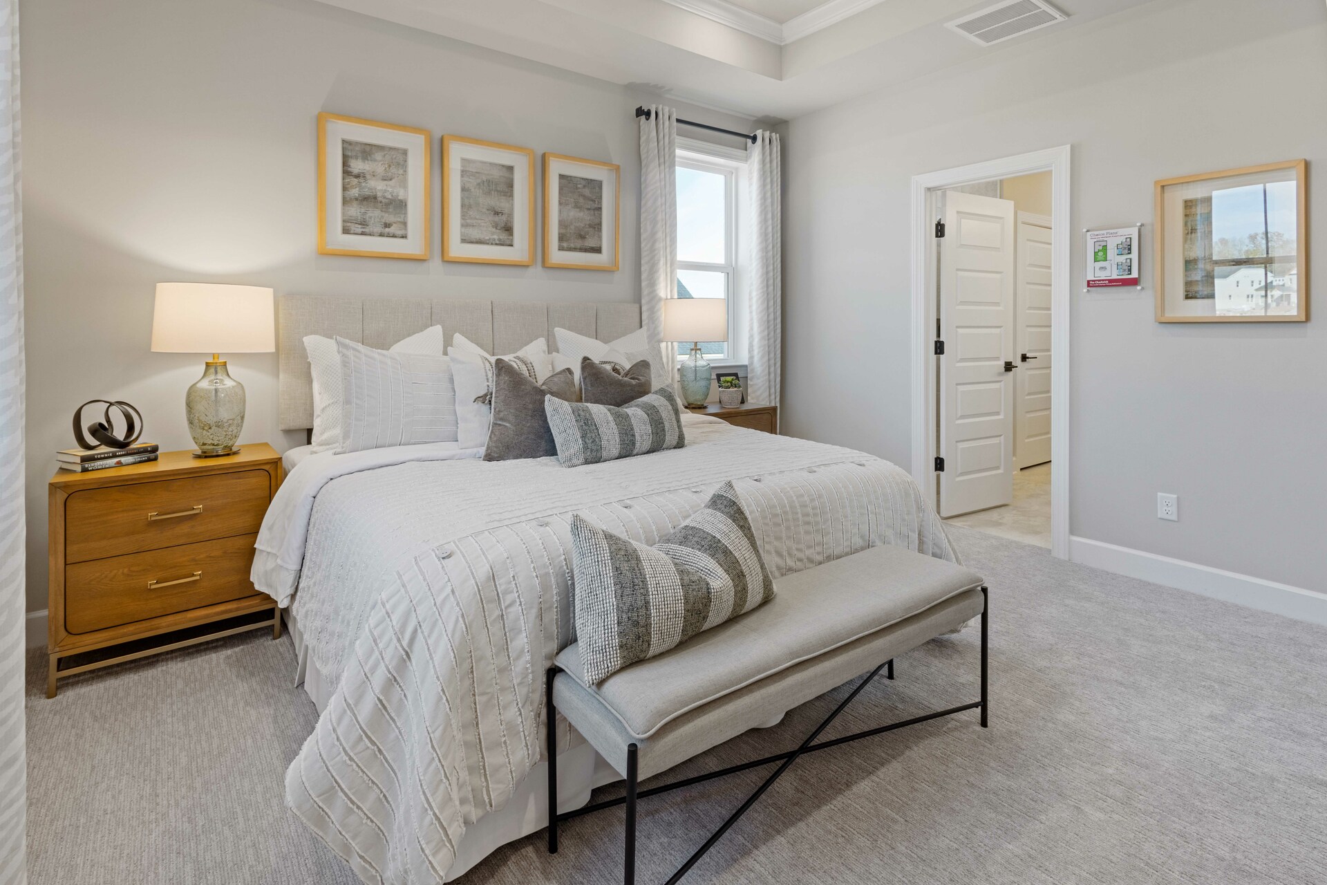 primary bedroom with large bed, nightstands, large windows, and a tray ceiling