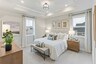 primary bedroom with large bed, nightstands, large windows, and a tray ceiling