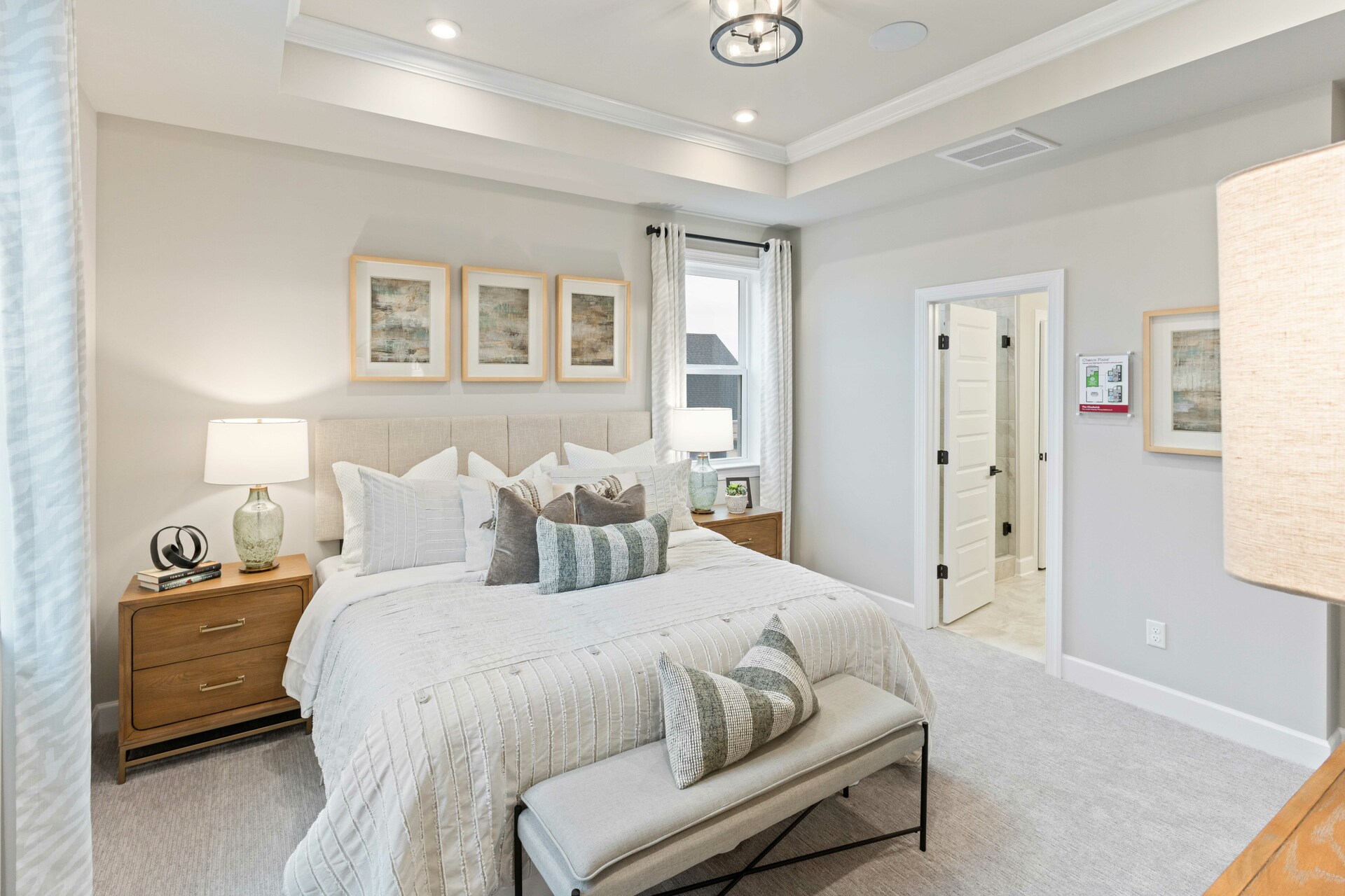 primary bedroom with large bed, nightstands, large windows, and a tray ceiling