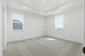 primary bedroom with light carpet, large windows, and a tray ceiling