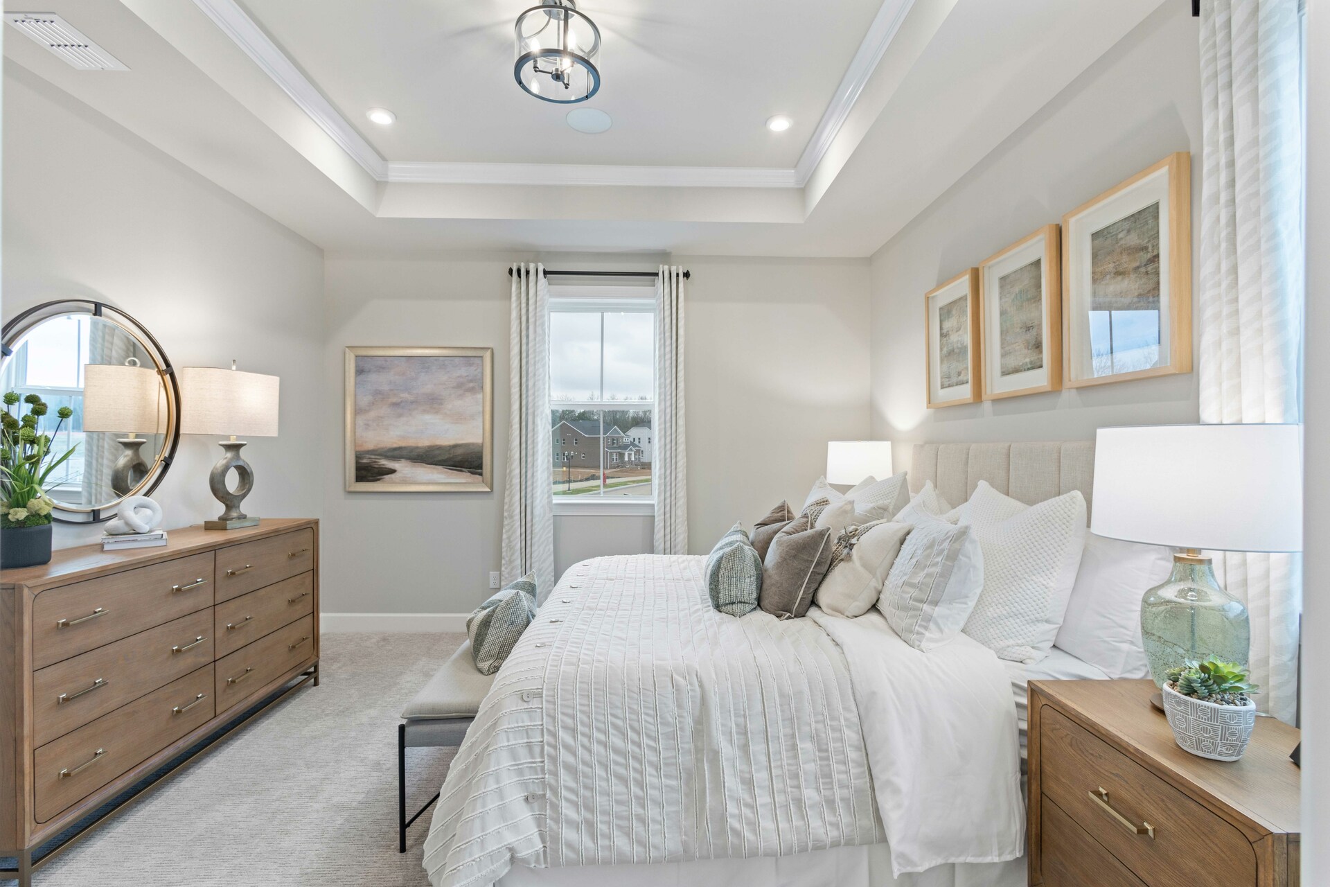 primary bedroom with large bed, nightstands, large windows, and a tray ceiling