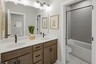 secondary bathroom with wood cabinets, white countertops, and a shower and tub combination