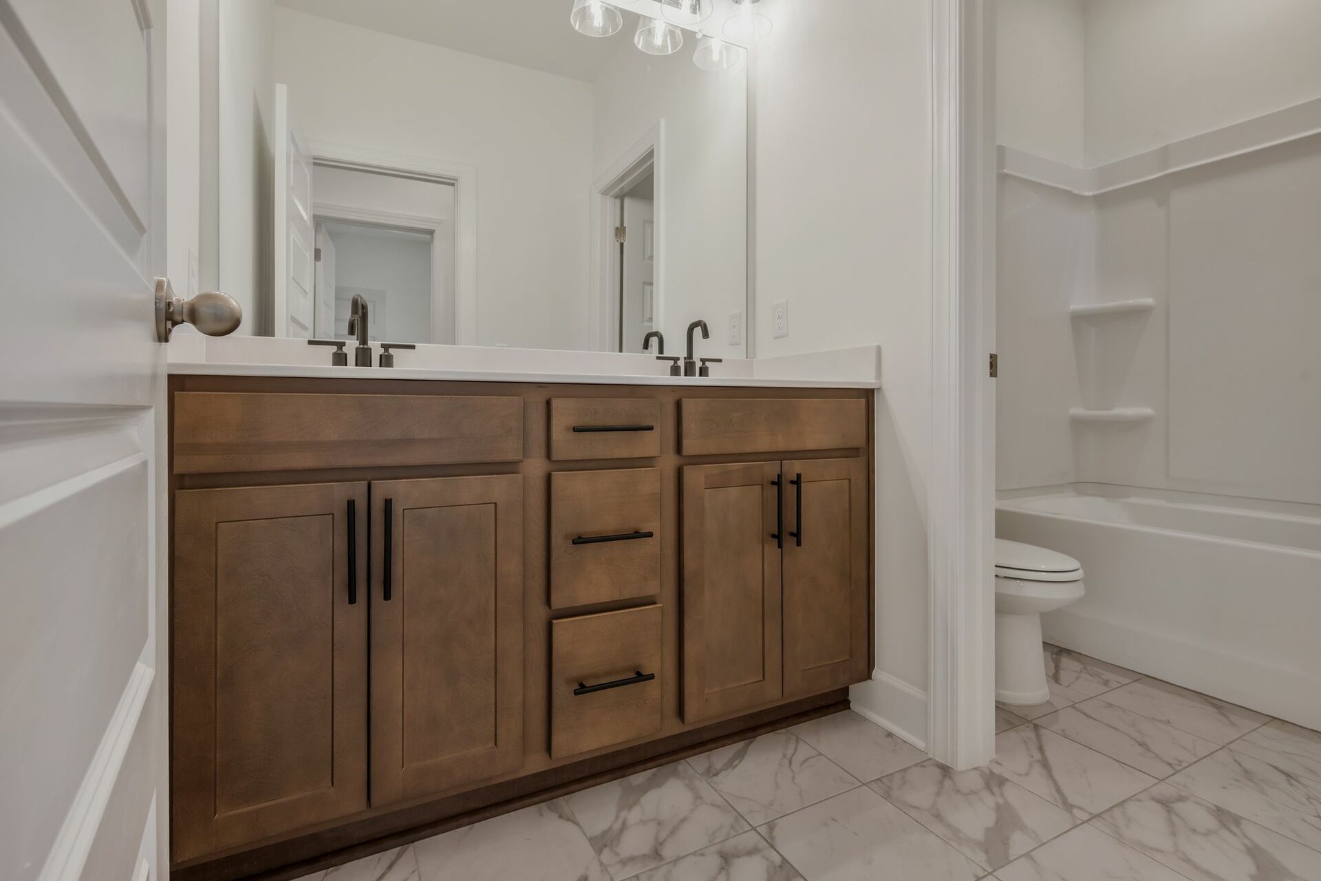 bathroom with tub shower, wood cabinets and black hardware