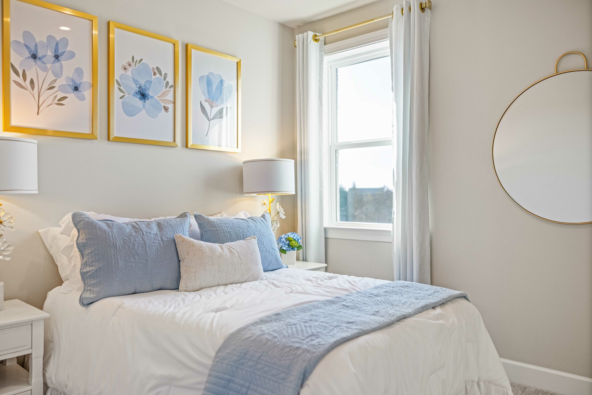 secondary bedroom with bed, nightstands, light blue accents, and a large window