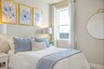 secondary bedroom with bed, nightstands, light blue accents, and a large window