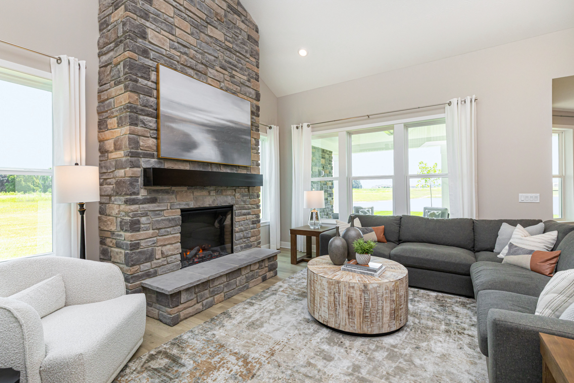 great room with tall stone fireplace and grey sectional 