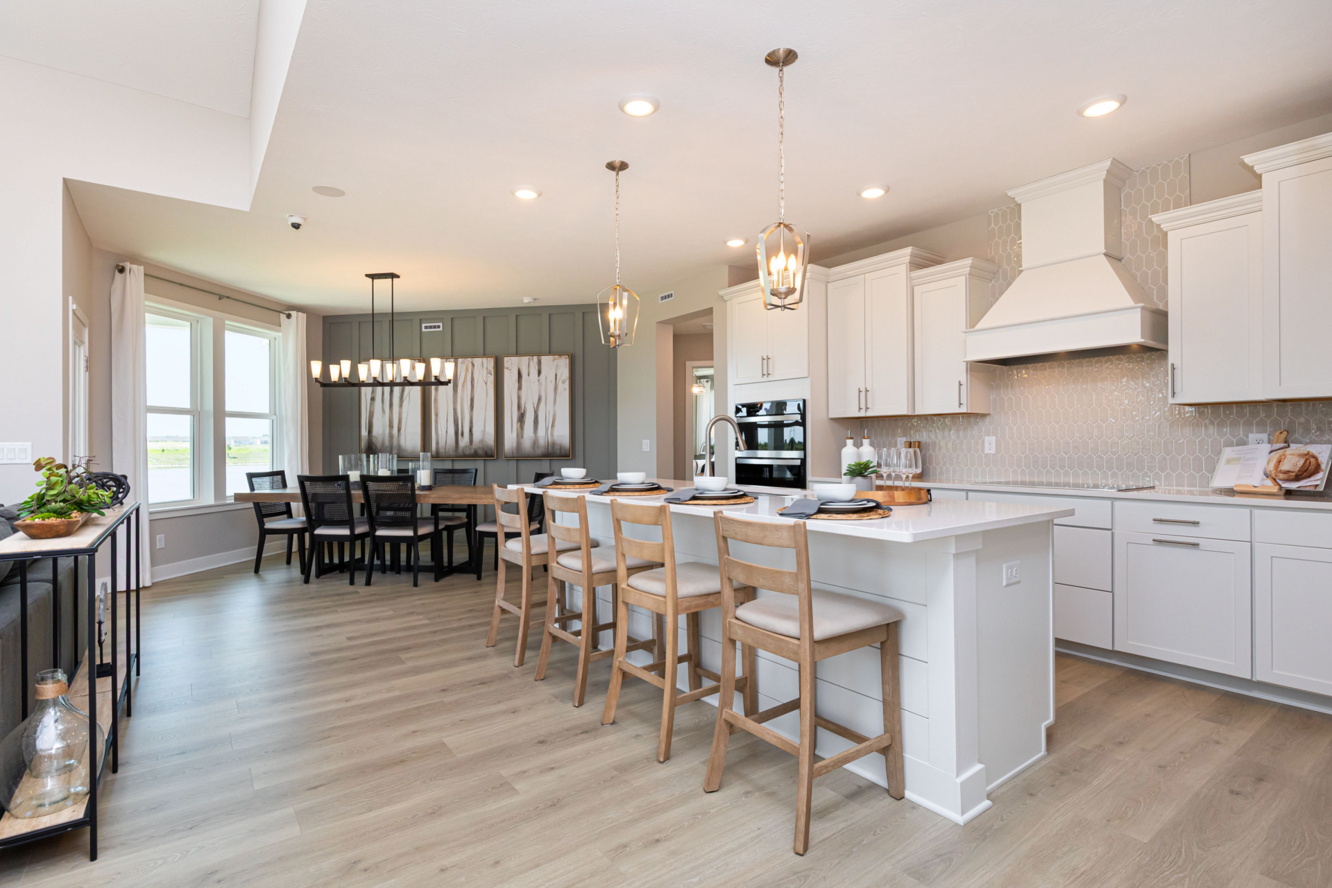 open-concept kitchen and dining area and pendant lighting, white cabinets and a green accent wall
