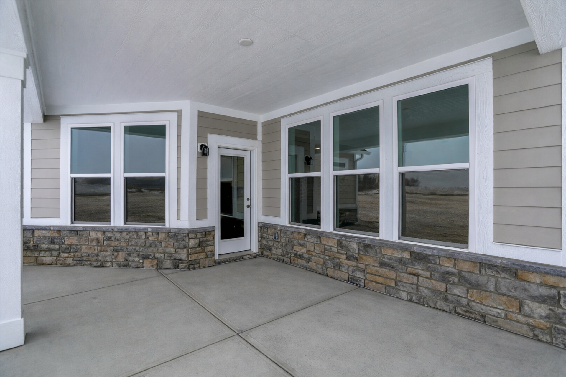 covered back patio with stone details and tan siding