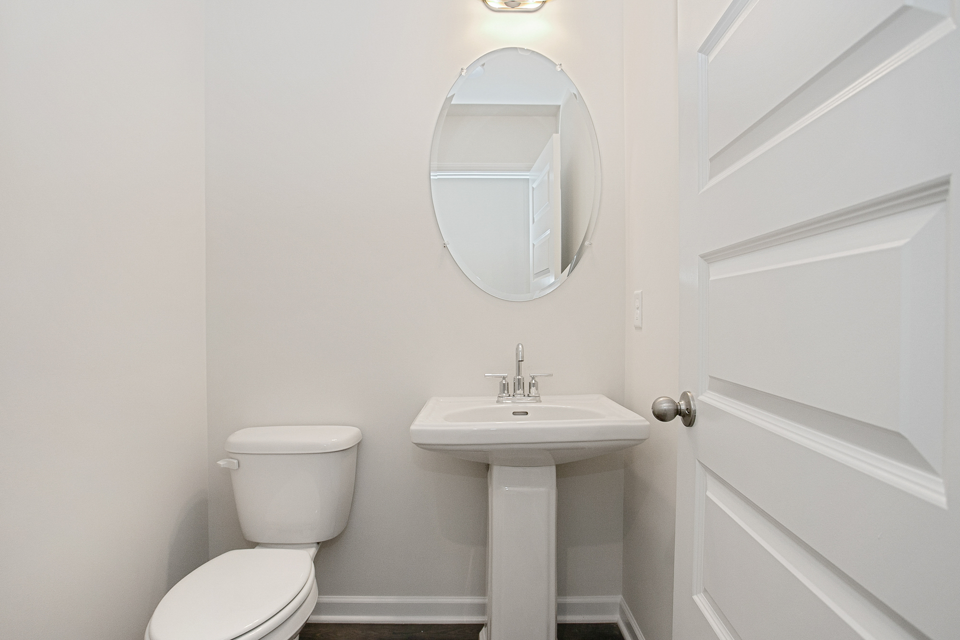 powder room with oval mirror and white finishes