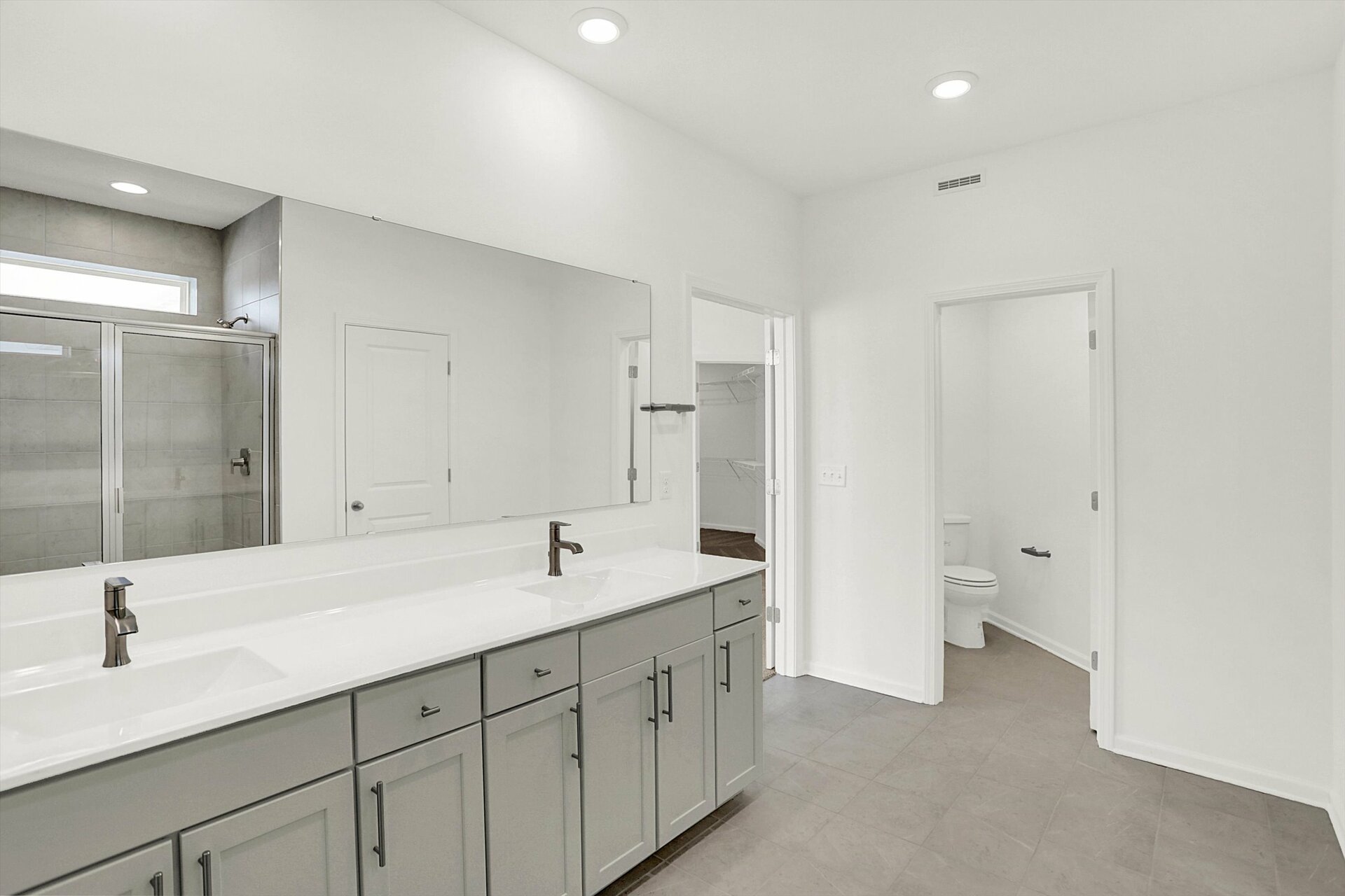 bathroom with dual sink vanity and gray tile flooring