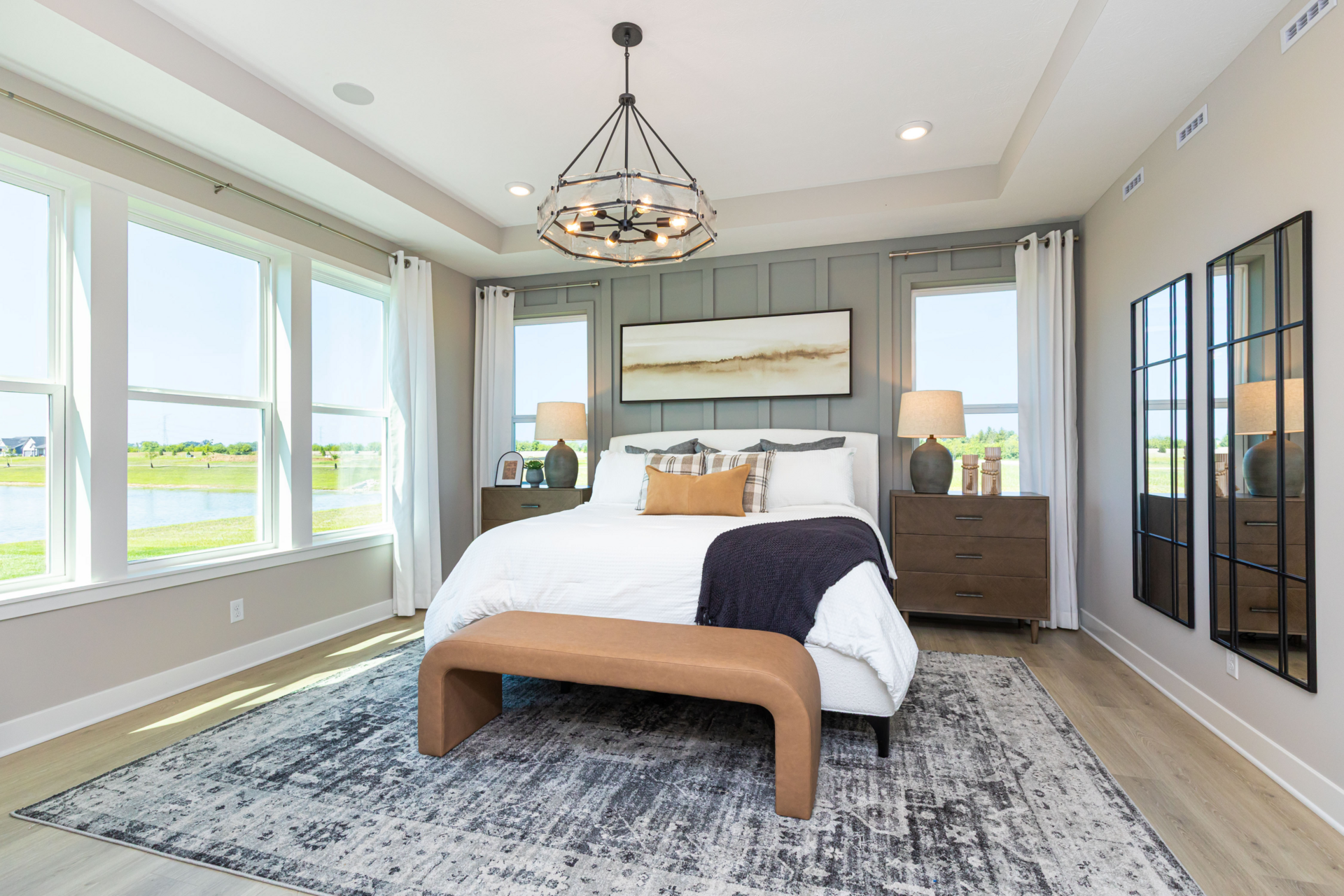 primary bedroom with leather modern ottoman and a sage green accent wall behind the bed