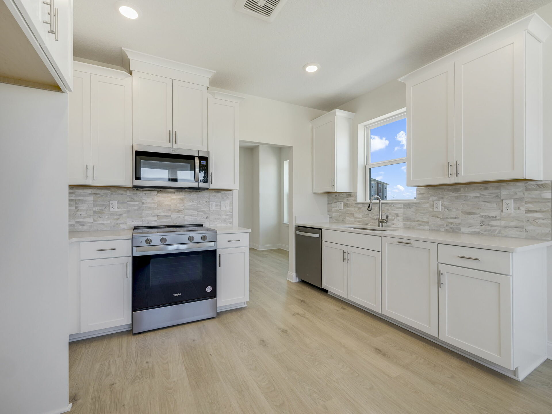 open kitchen with stainless steel appliances and tile backsplash.