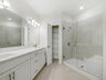 dual sink vanity, water closet, and semi-frameless shower