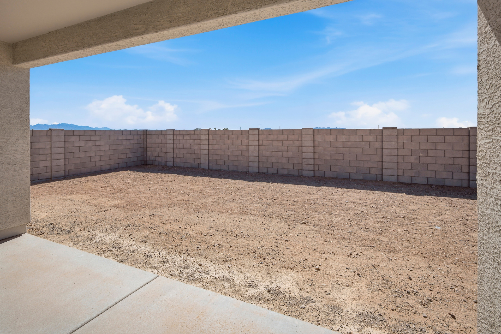 spacious dirt backyard with a concrete block wall